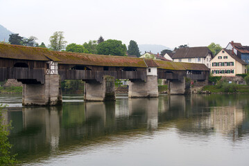 Fototapeta na wymiar Covered wooden bridge over the Rhine River at Stein, Canton Aargau, and Bad Säckingen, Baden-Württemberg, on a cloudy spring day. Photo taken May 6th, 2022, Stein, Switzerland.