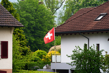Swiss flag blowing in the wind at Swiss village Stein, Canton Aargau, on a cloudy spring day. Photo...
