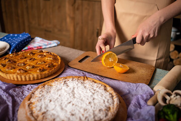 a girl cuts a lemon with a knife on the background of pies
