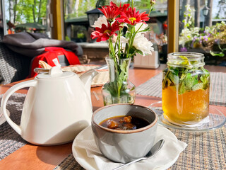 Freshly brewed hot tea with fresh mint and white cherry jam in a rosette on a summer open veranda...