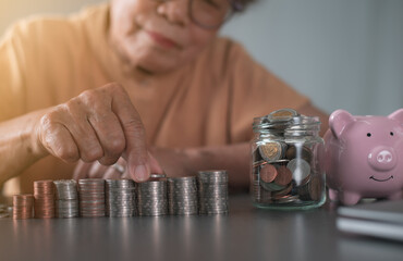 An old woman arrange piles of coins on a wooden table.