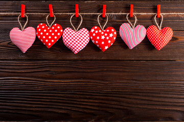Valentine fabric hearts hanged on rope on dark wooden background