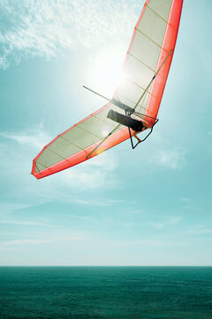 Hang gliding into the sun with a red glider