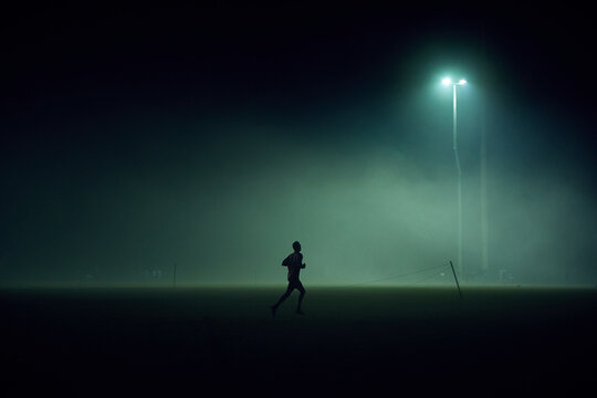 Person playing on sport oval in fog at night