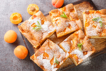 slices of apricot sponge pie with fresh mint on a rustic wooden board closeup on the table....