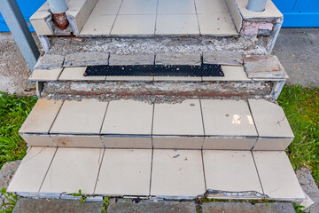 Destruction of cement foundation and stairs made of concrete, licked tiles are broken