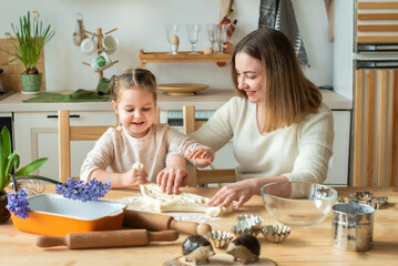 girl and woman cook at home. in a kitchen, a child stirs flour, knead the dough on the table by hand.