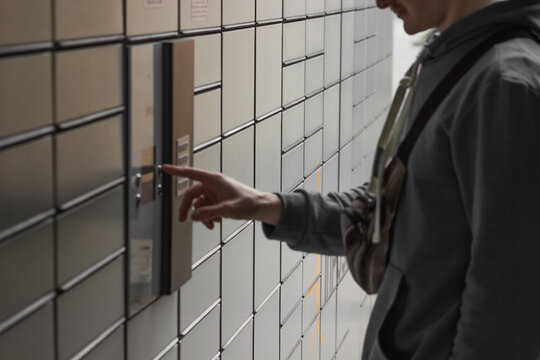 Shopping locker inPost with man's hand entering code to open it. E-commerce shipping and delivery.