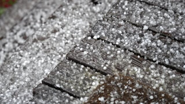 Hail covering the ground as it falls in slow motion during storm as it bounces off the surface.