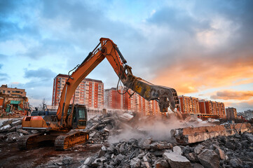 Excavator with concrete crusher on rig at demolition site