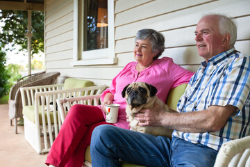 Old couple sitting on the front porch with their pet dog