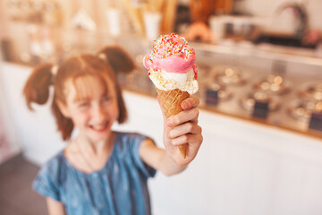 Cute little girl eating ice cream in cafeteria. Child holding icecream. Kid and sweets