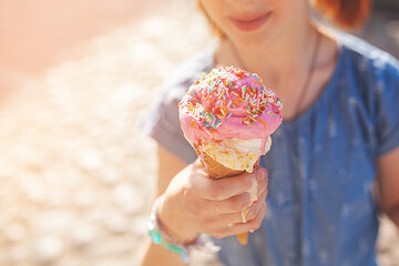 Cute girl eating ice cream on summer background outdoors. closeup portrait of adorable redhaired...