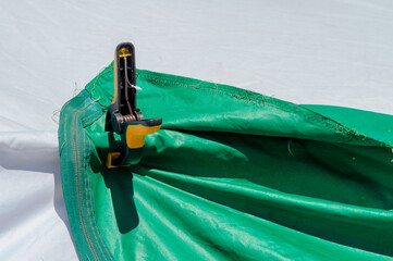 A large clothespin holds two tarpaulins together