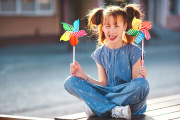 Cute funny litle girl with windmill. Kid holding windmill. Summertime background.