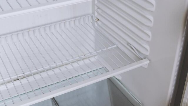 The man's hand opens an empty refrigerator with the word crisis on it and takes one single banana. Conceptual 4k raw video. Idea of ​​economic crisis, food shortage, poverty.