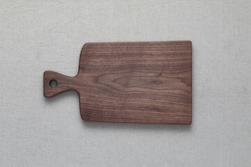 Walnut handmade wooden cutting board on burlap background.
