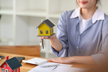 Financial advisor or real estate agent hands holding house model. Insurance and real estate concept