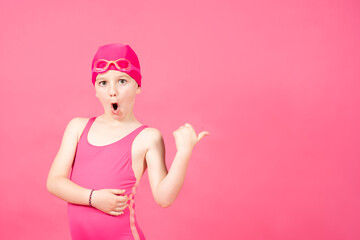 Little surprised swimmer girl pointing at vivid pink copy space. swimming course concept.