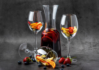 Glass of red Sangria and fruits on dark stone table