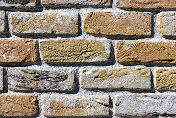 Ancient handmade brick wall of various colors up close