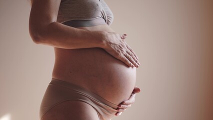 pregnant woman. health pregnancy sunlight motherhood procreation concept. close-up belly of a pregnant woman. woman waiting for a newborn baby. pregnant woman holding her belly indoors