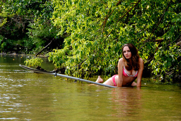 Beautiful young Ukrainian woman on the river under a tree in a red swimsuit