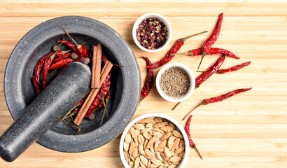 Home made sun dried red chilli and spicy herbs in granite mortar and pestle on wooden board, close up shot, Flat lay