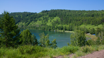 Picturesque lake surrounded by mountains with green grass and trees.