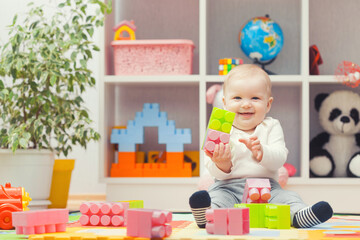 baby playing with colourful building blocks at home or kindergarten