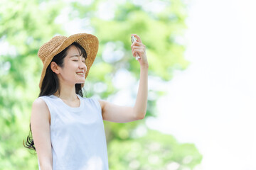 日焼け止め・虫除けスプレーする女性（笑顔・顔）
