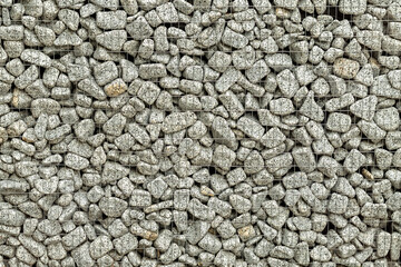 Textured background of a stone wall with iron netting. Stone wall in wire frame.