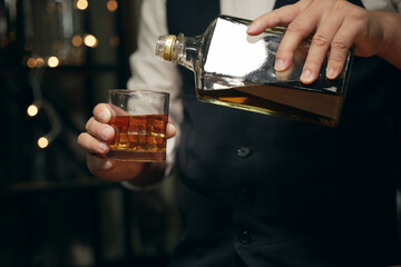 Barman pouring whiskey glass beautiful night