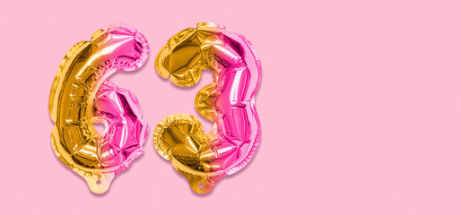 Rainbow foil balloon number, digit sixty three on a pink background. Birthday greeting card with inscription 63. Top view. Numerical digit. Celebration event, template. Banner