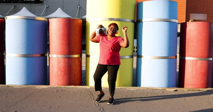 Happy woman with ghetto blaster singing and dancing in the street