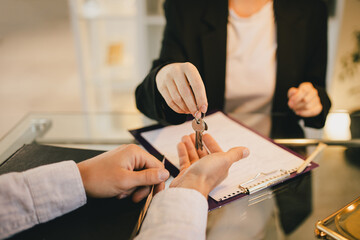 Happy couple buying a property, recieving a key from new apartment from real estate agent..