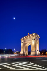 The Arcul de Triumf, a triumphial arch in Bucharest, Romania, at night - obrazy, fototapety, plakaty