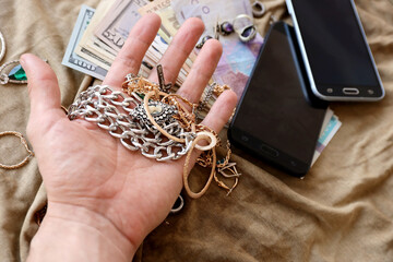 Marauders hand with bunch of stolen jewelry, money and smartphones on military uniform cloth...