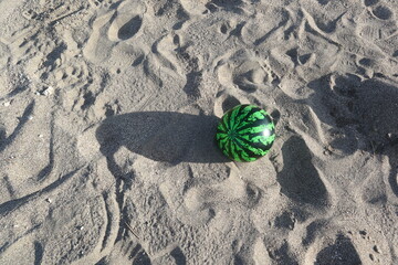 a green plastic ball on the sand beach design for leisure and outdoor activity
