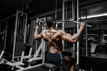 Handsome power athletic bodybuilder training pumping up muscles in gym - obrazy, fototapety, plakaty