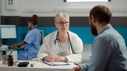 Obraz premium Senior doctor writing consultation information on checkup report to receive treatment from health care system. Prescription medicine on paperwork documents to treat diagnosis.