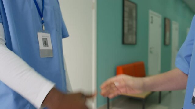 Medical nurses talking in hosptal corridor shaking hands