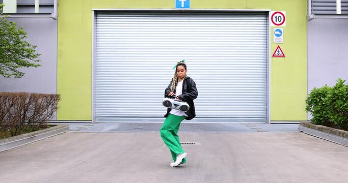 Young woman with ghetto blaster dancing in front of garage gate