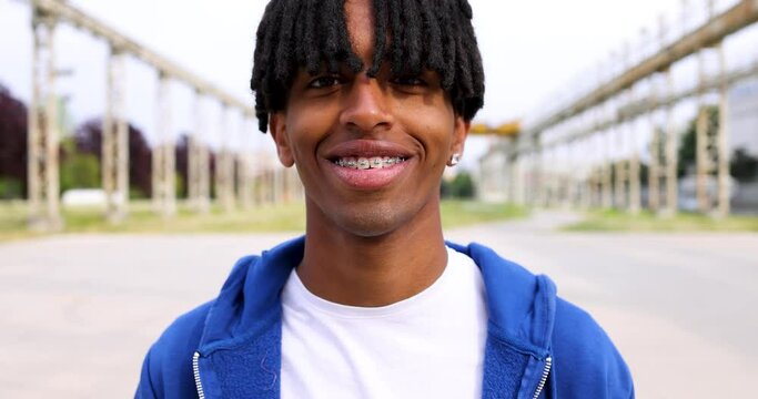 Young man with locks smiling showing braces