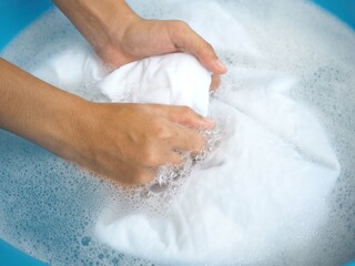Fototapeta premium Shirt washing with detergent bubble in wash tub. closeup photo, blurred.