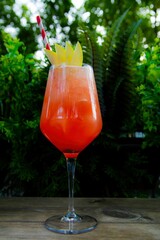 orange colored summer cocktail in a glass on an outdoor table