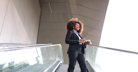 Businesswoman with digital tablet standing on escalator - Powered by Adobe
