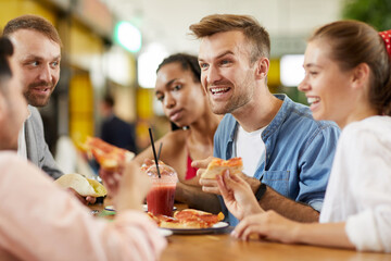 Expressive young guy emotionally reacting to friends news while they having lunch together in cafe