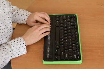 A blind woman uses a computer with a Braille display and a computer keyboard. Inclusive device.