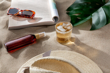 leisure and summer holidays concept - open magazine, sunscreen, glass of ice drink and sunglasses...